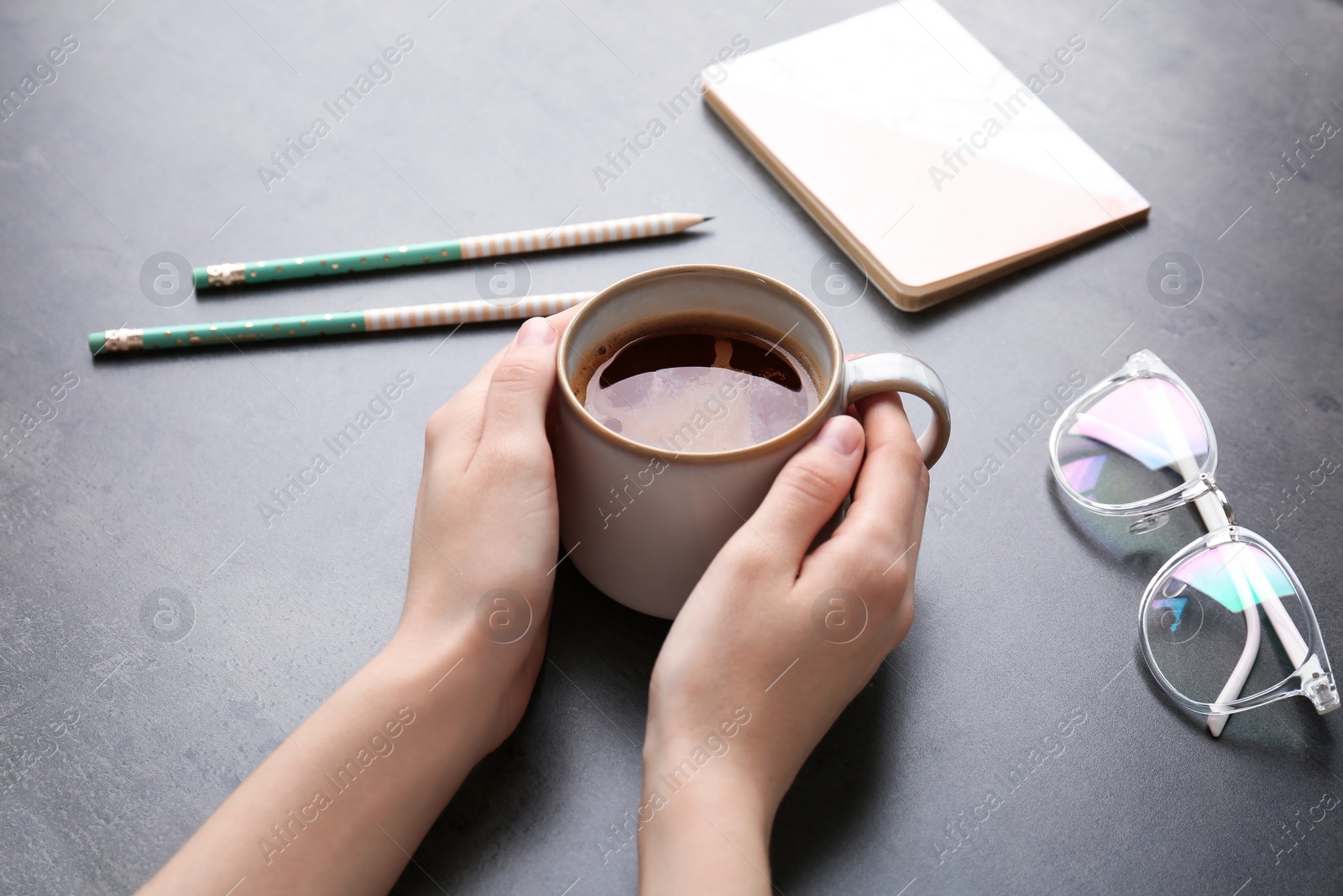 Photo of Young woman with cup of delicious hot coffee at table