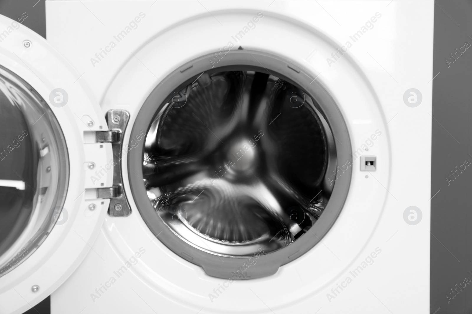 Photo of Open washing machine on grey background, closeup. Laundry day