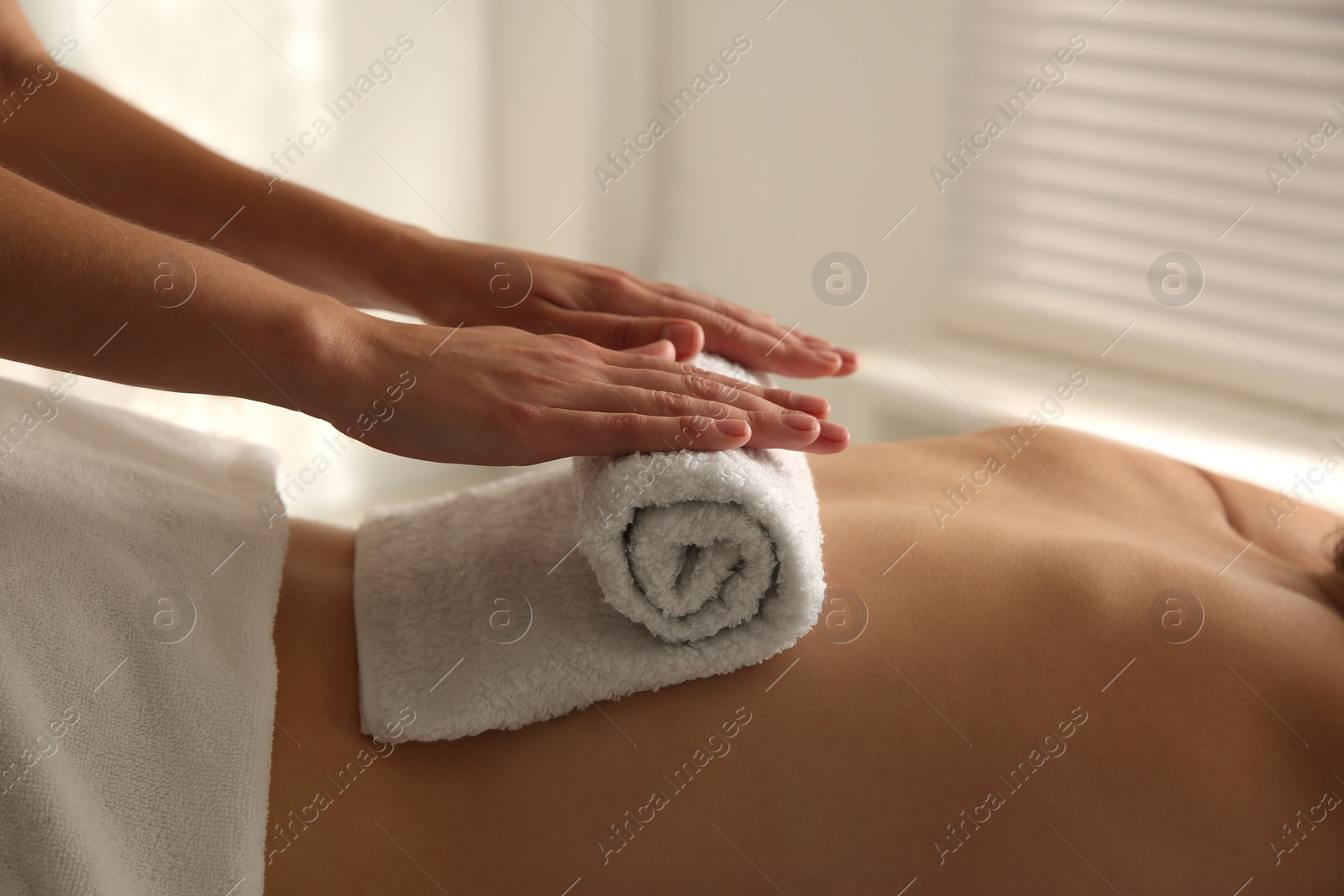 Photo of Young woman receiving hot towel massage in spa salon, closeup