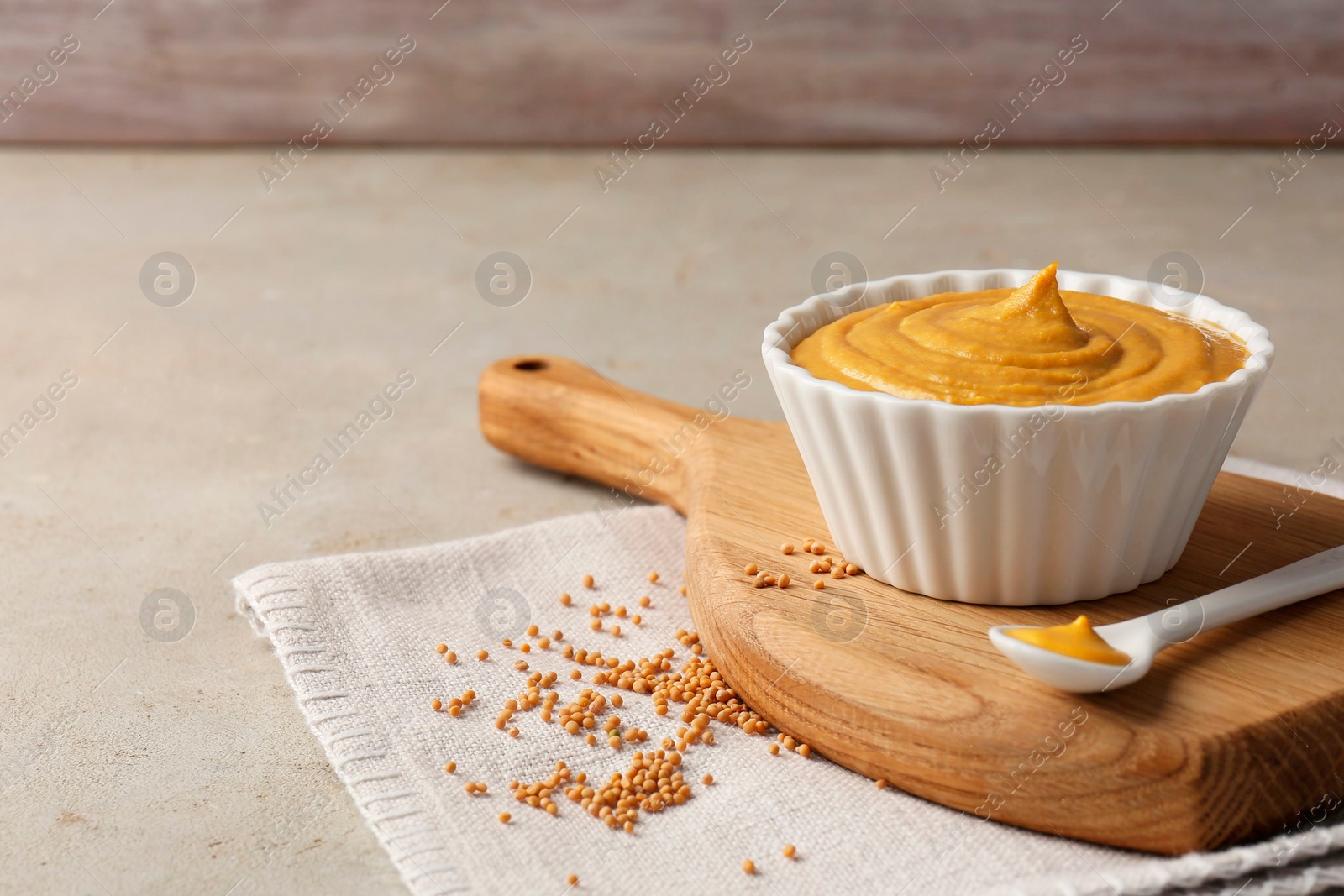 Photo of Tasty mustard sauce and dry seeds on light textured table, space for text