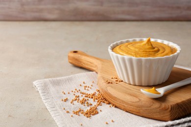 Tasty mustard sauce and dry seeds on light textured table, space for text