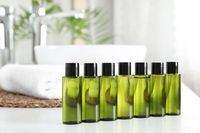 Photo of Mini bottles with cosmetic products on white table in bathroom