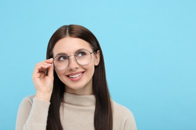 Photo of Smiling woman in stylish eyeglasses on light blue background. Space for text