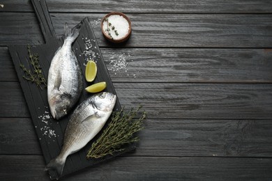 Photo of Raw dorada fish on black wooden table, flat lay. Space for text