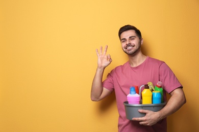 Man with basin of detergents on color background. Space for text