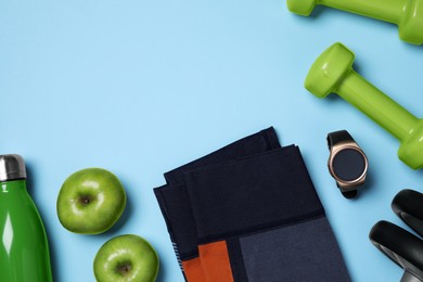 Photo of Sports equipment, apples and clothes on light blue background, flat lay with space for text. Personal training