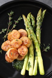Photo of Delicious fried scallops with asparagus and thyme on plate, top view