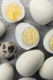 Peeled and unpeeled hard boiled quail eggs on grey table, flat lay