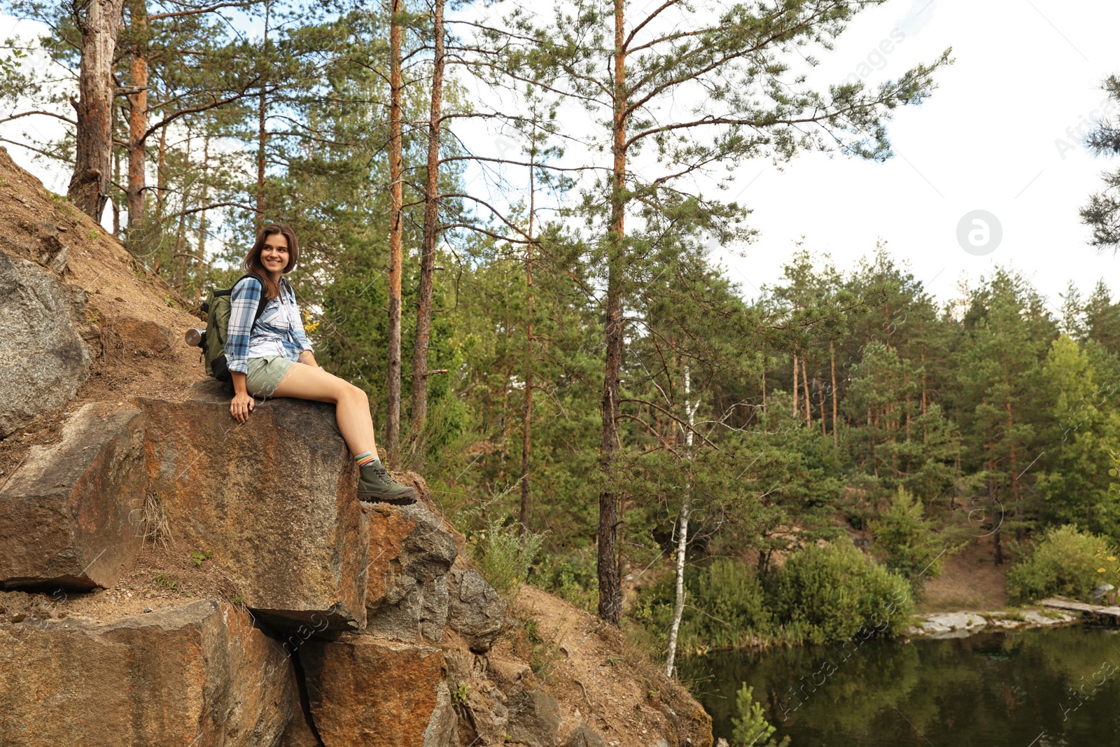 Photo of Young woman on rocky mountain near forest. Camping season