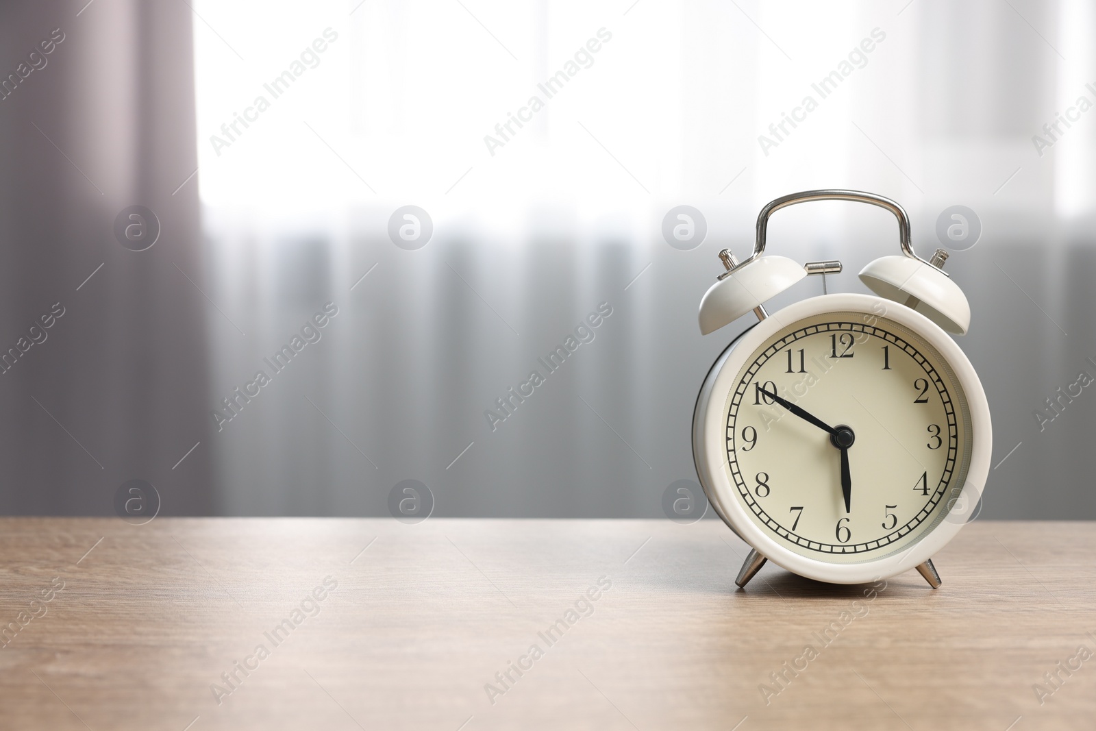 Photo of White alarm clock on wooden table indoors, space for text