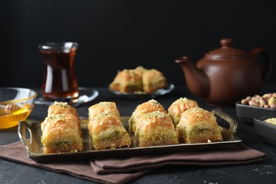 Photo of Delicious fresh baklava with chopped nuts served on dark textured table. Eastern sweets