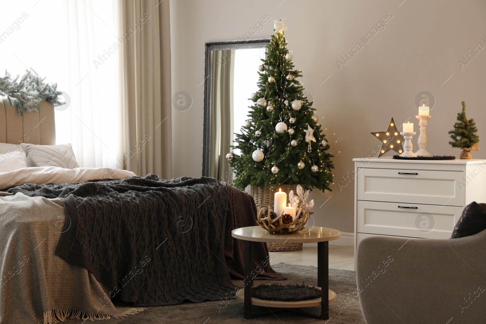 Photo of Beautiful decorated Christmas tree with fairy lights in bedroom interior