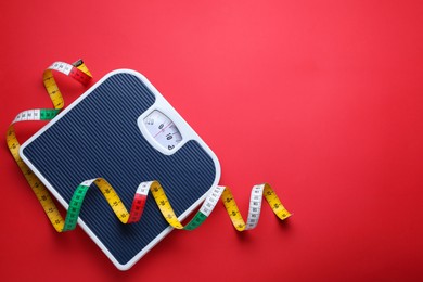 Photo of Scales and measuring tape on red background, top view. Space for text