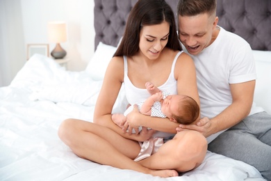Photo of Happy couple with their newborn baby on bed