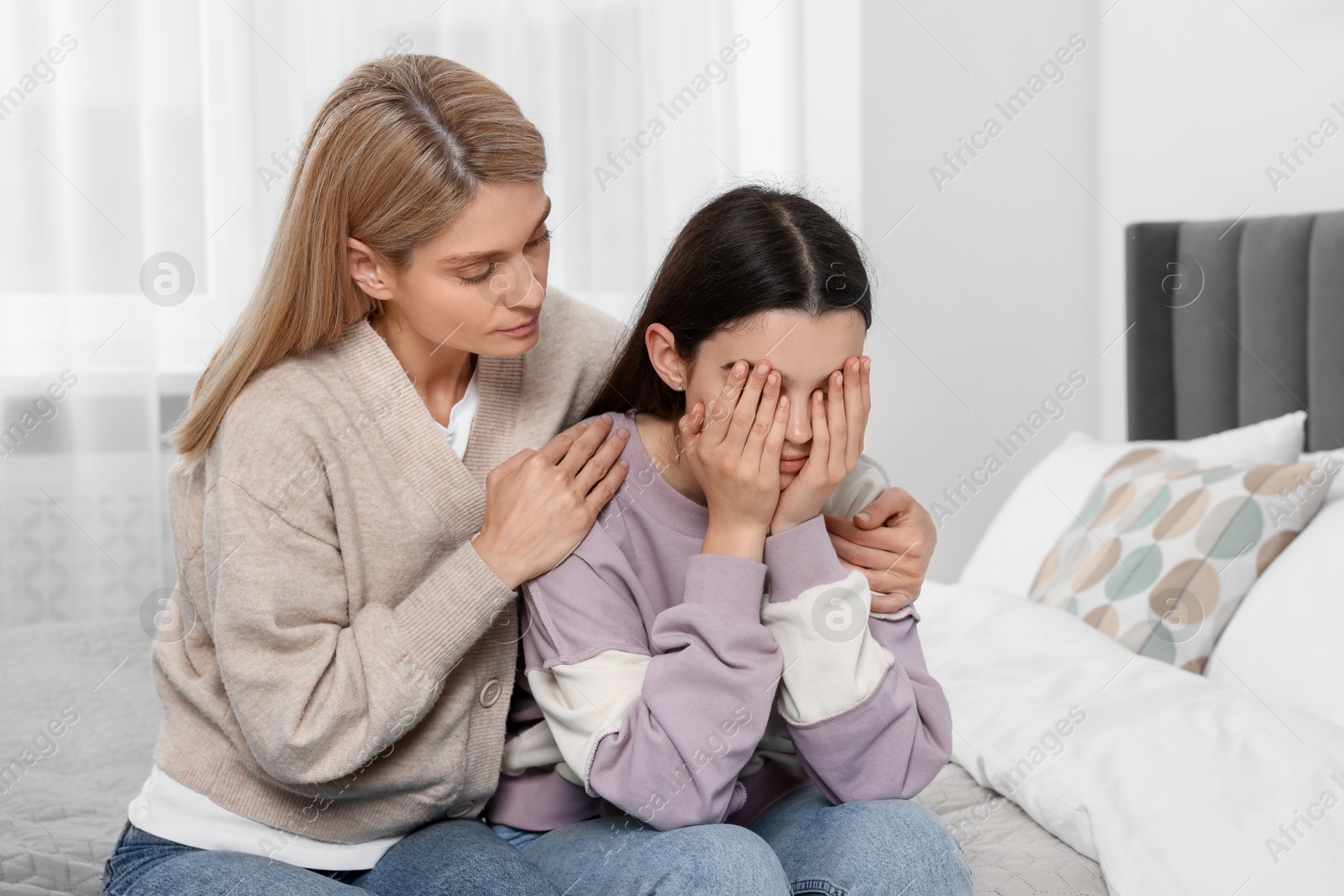 Photo of Mother consoling her upset daughter in bedroom. Teenager problems