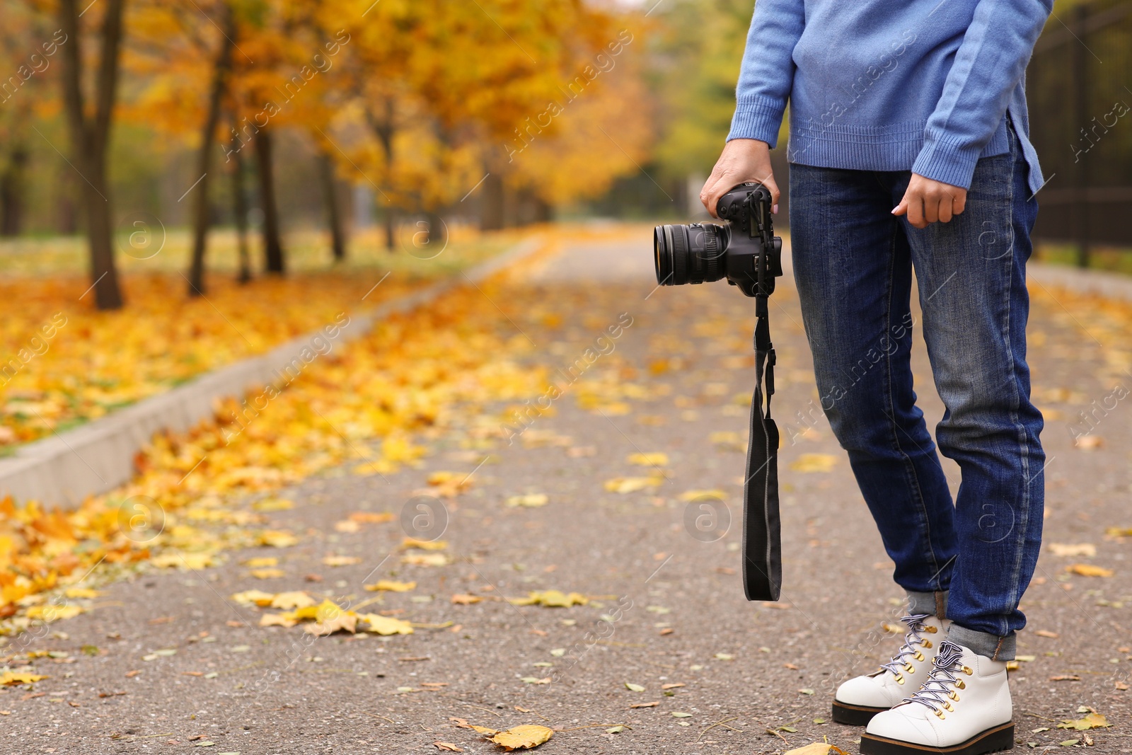 Photo of Photographer with professional camera outdoors on autumn day, closeup. Space for text