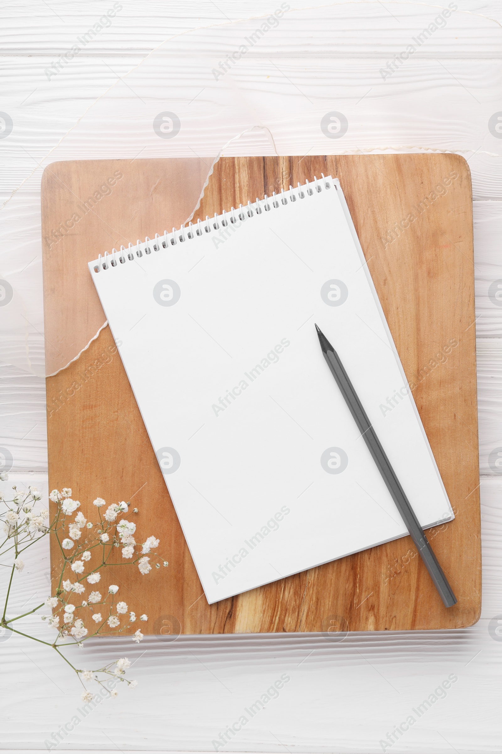 Photo of Guest list. Notebook, pencil, gypsophila and ribbon on white wooden background, flat lay