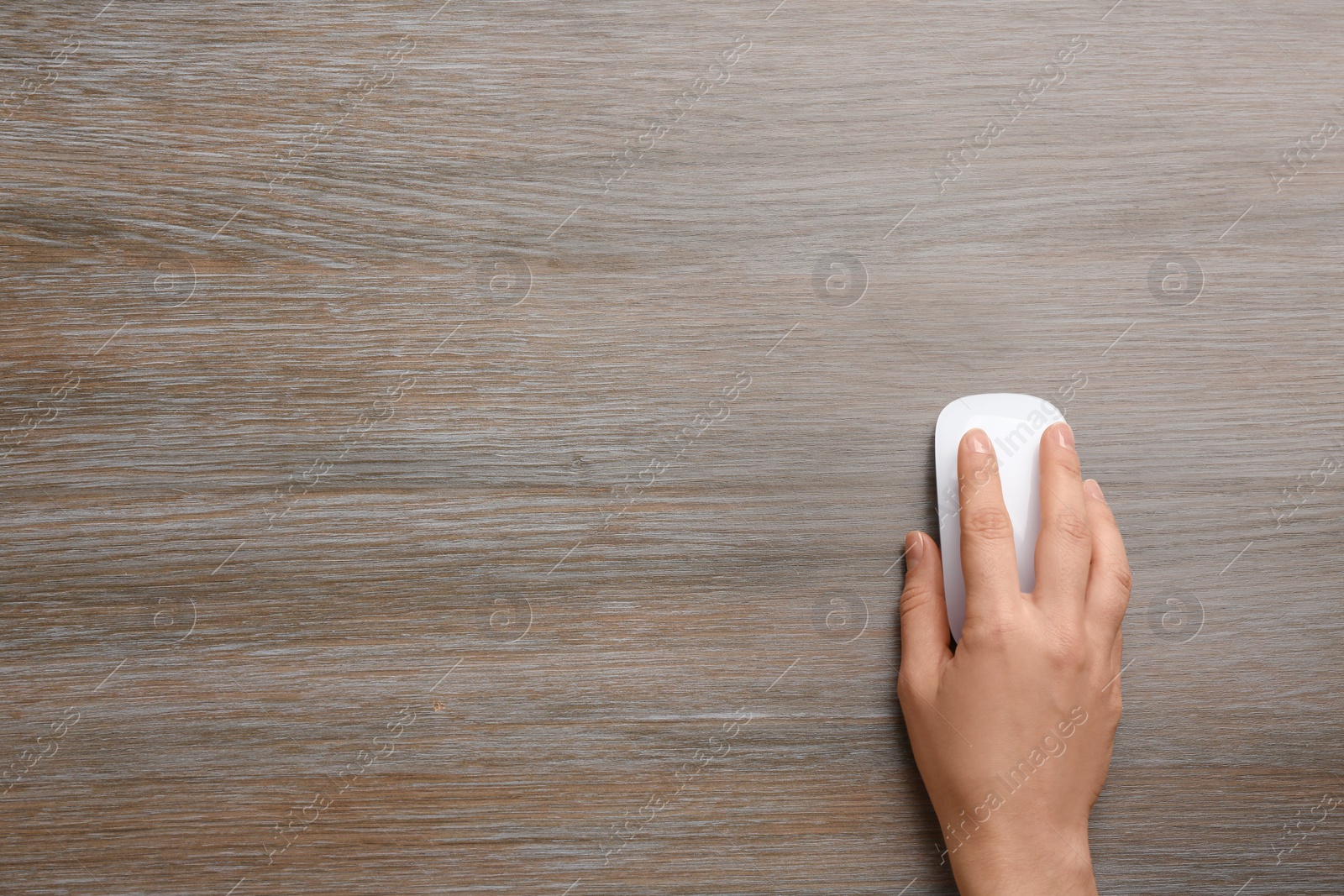 Photo of Woman using computer mouse on wooden table, top view. Space for text