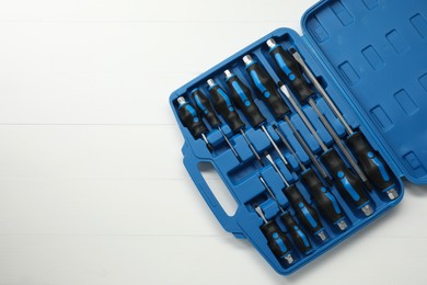 Photo of Set of screwdrivers in open toolbox on white wooden table, top view. Space for text