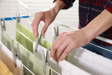 Woman hanging clean terry towels on drying rack indoors, closeup