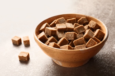 Photo of Bowl with cubes of brown sugar on table