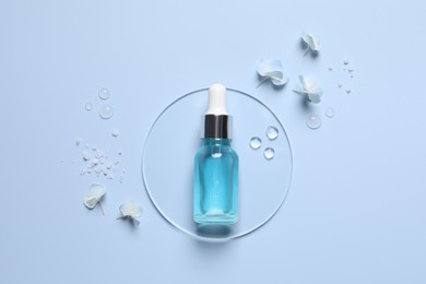 Bottle of cosmetic serum, flowers and sea salt on light blue background, flat lay