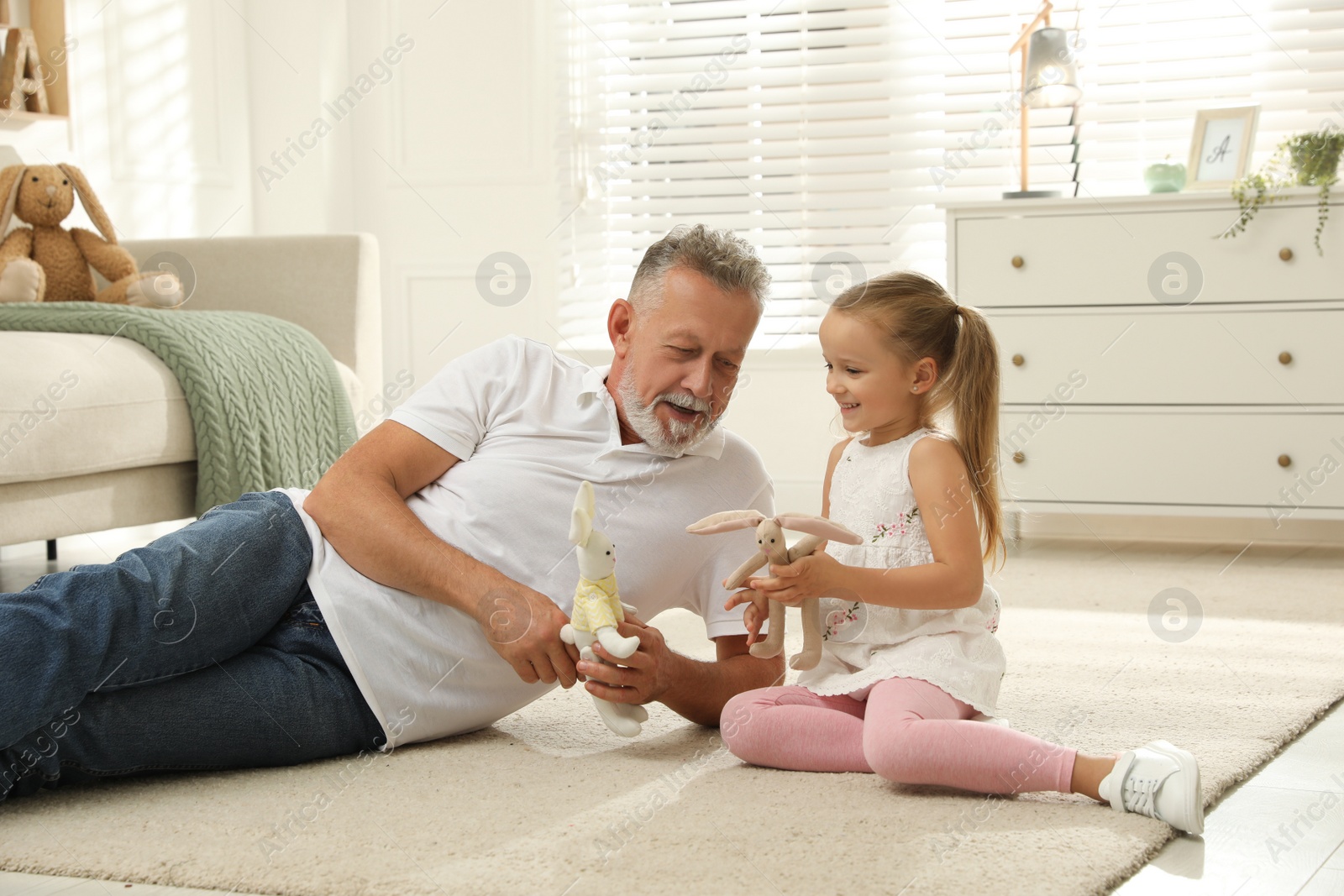 Photo of Happy grandfather and his granddaughter playing with toys together at home
