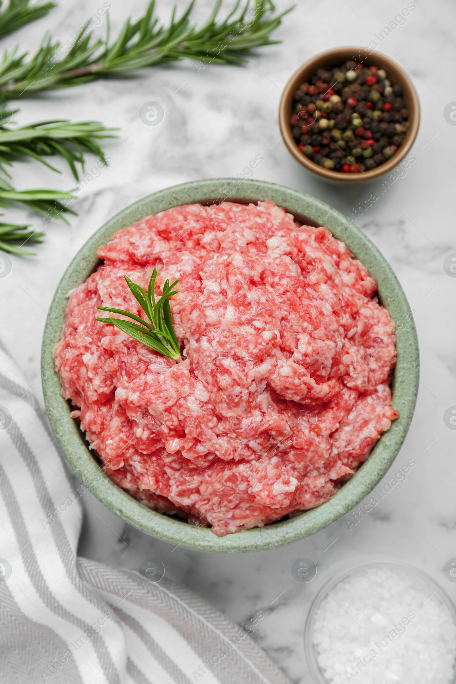 Photo of Bowl of raw fresh minced meat with rosemary and spices on white marble table, flat lay