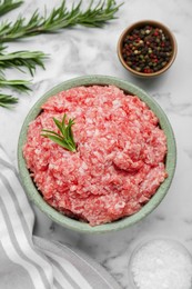 Photo of Bowl of raw fresh minced meat with rosemary and spices on white marble table, flat lay