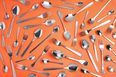 Photo of Set of new silver cutlery on coral background, flat lay