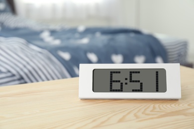 Photo of Digital alarm clock on table in bedroom. Time of day