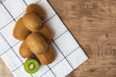 Photo of Heap of whole and cut fresh kiwis on wooden table, top view. Space for text