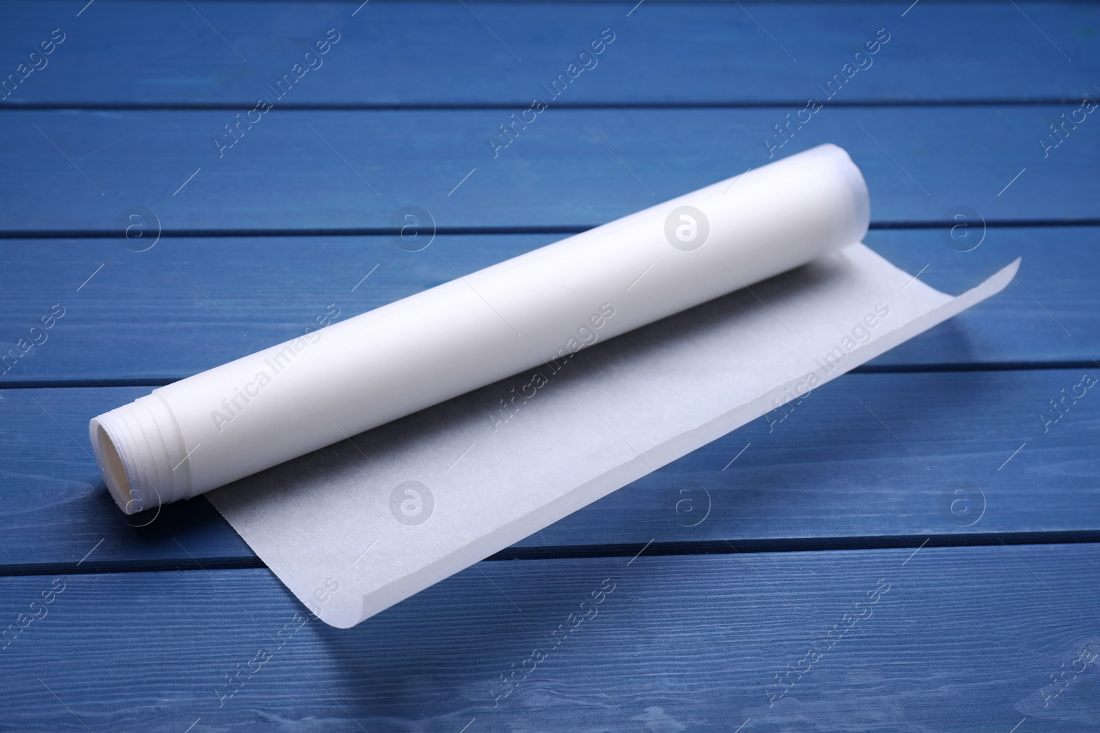 Photo of Roll of baking paper on blue wooden table