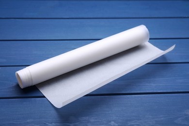Photo of Roll of baking paper on blue wooden table