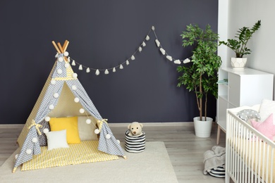 Photo of Cozy baby room interior with play tent and toys