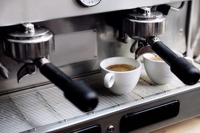 Coffee machine with cups on drip tray, closeup