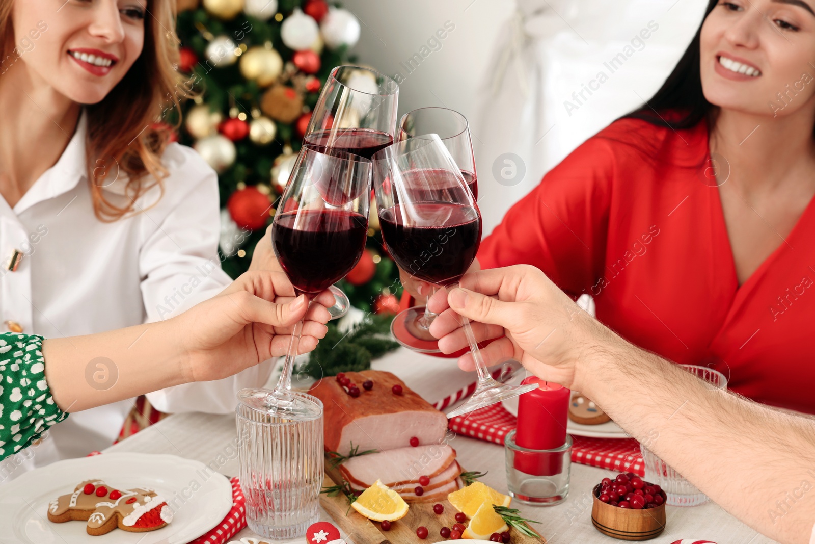 Photo of Happy family with their friends clinking glasses at festive dinner indoors. Christmas Eve celebration