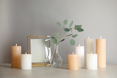 Composition with burning candles on table against light background