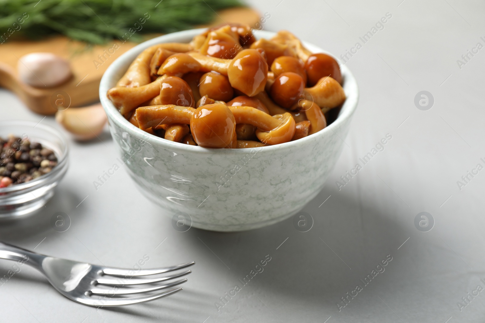 Photo of Tasty marinated mushrooms in bowl on grey table, closeup
