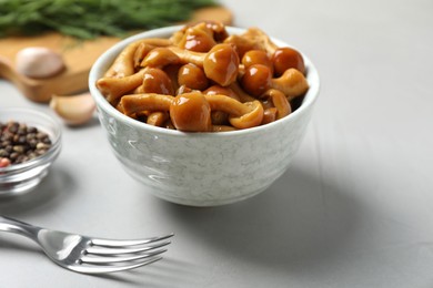 Tasty marinated mushrooms in bowl on grey table, closeup
