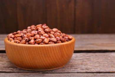 Photo of Bowl with dry kidney beans on old wooden table, closeup. Space for text