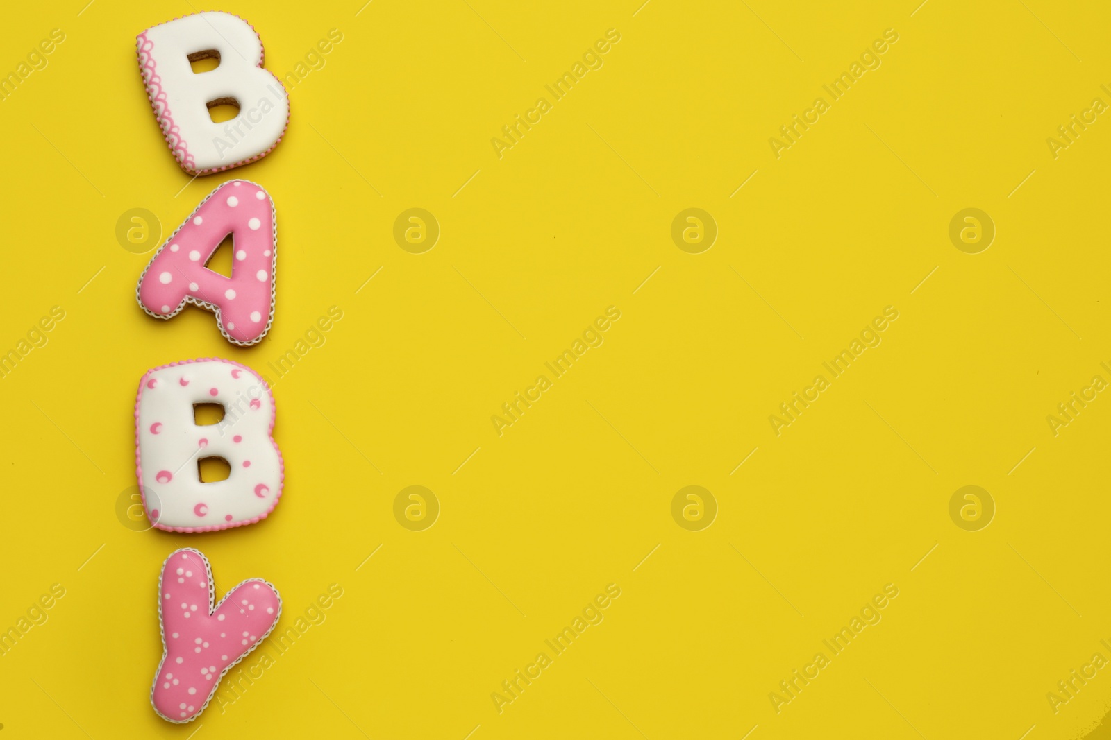 Photo of Word BABY made of tasty cookies on yellow background, flat lay. Space for text