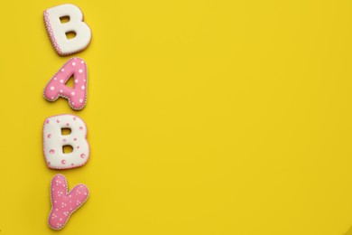 Photo of Word BABY made of tasty cookies on yellow background, flat lay. Space for text