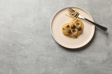 Photo of Heart made of tasty spaghetti, olives, cheese and fork on light grey table, top view. Space for text