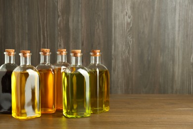 Vegetable fats. Different oils in glass bottles on wooden table, space for text