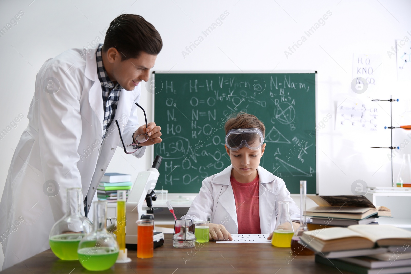 Photo of Teacher with pupil at chemistry lesson in classroom