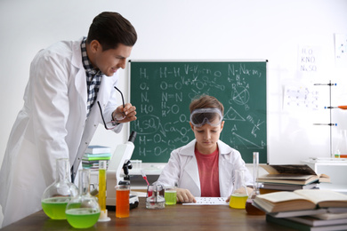 Teacher with pupil at chemistry lesson in classroom