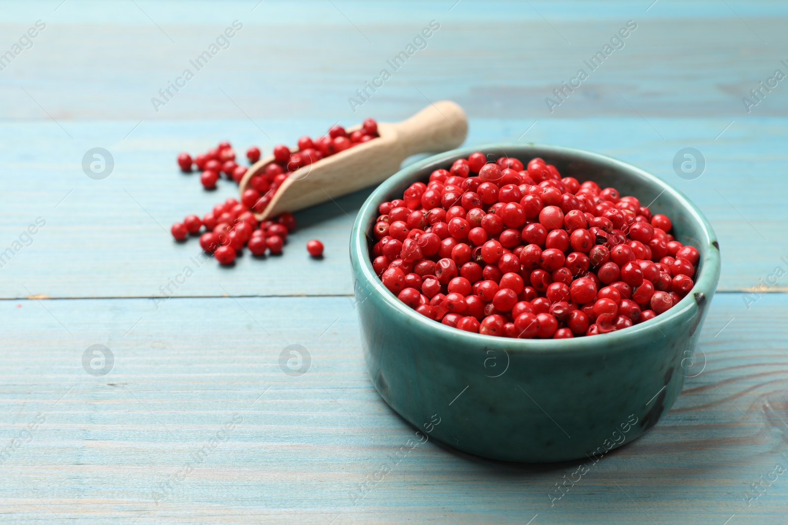 Photo of Aromatic spice. Red pepper in bowl and scoop on light blue wooden table, closeup. Space for text