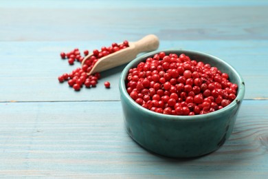 Aromatic spice. Red pepper in bowl and scoop on light blue wooden table, closeup. Space for text