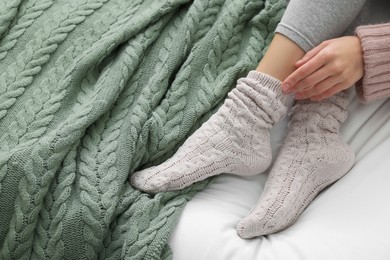 Photo of Woman wearing warm socks in comfortable bed, above view. Space for text